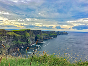 The Cliffs of Moher under a cloudy sky at sunset