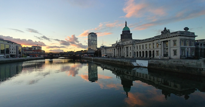 A view of the Liffey river at dusk, with the surrounding architecture reflected in the water