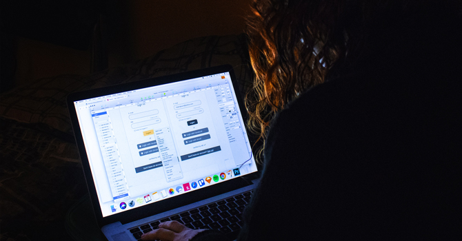 A girl works on her computer in a dark room