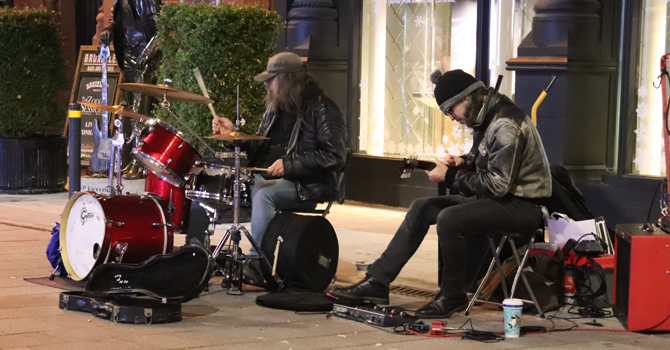 Two buskers play guitar and drums on a street in Dublin