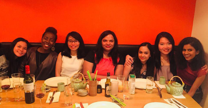 7 women sit at table after finishing dinner, smiling to camera