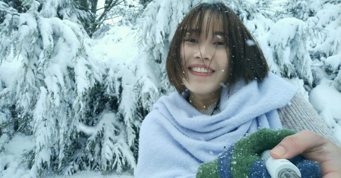 Student wrapped in big scarf smiling in front of snowy backdrop