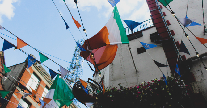 Irish flags attached to bunting in front of a clear sky