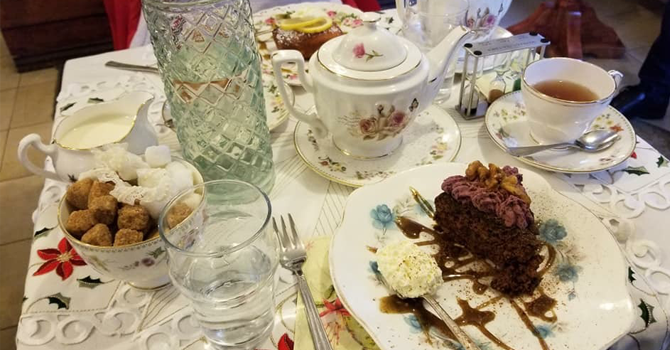 A table full of rich cakes and china teapots and cups