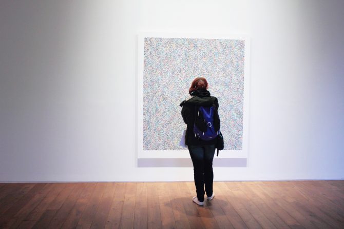 Girl with backpack standing in front of a painting 