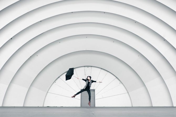 Person struggling with umbrella in white amphitheatre