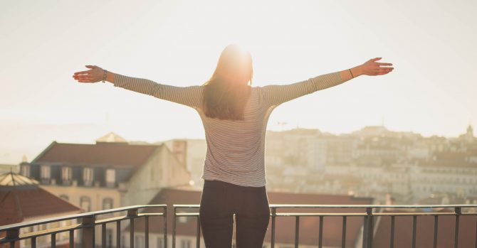 Woman standing on a balcony in the sunshine