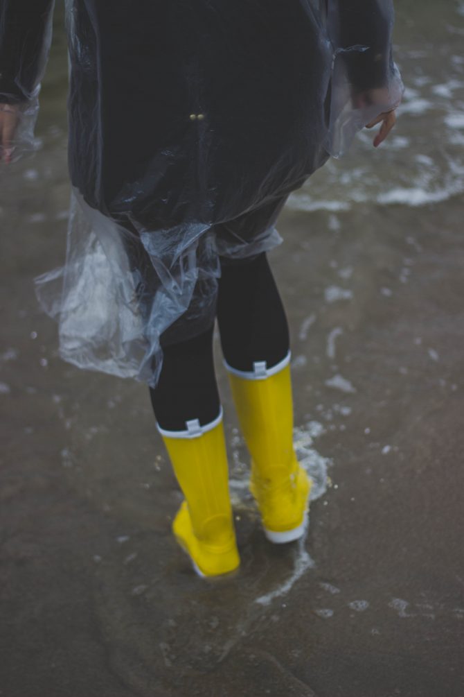 Person wearing raincoat and wellies in rain 