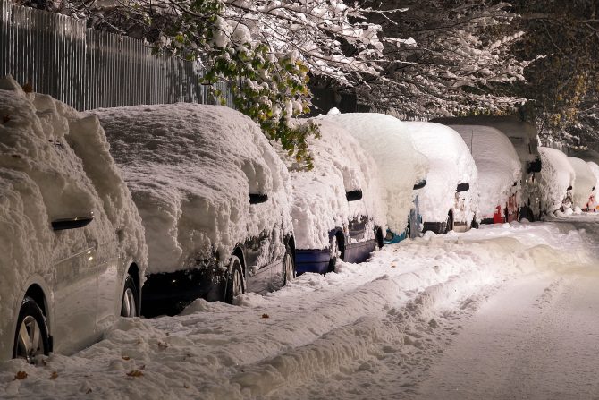 Line of cars on a road covered in a heavy blanket of snow