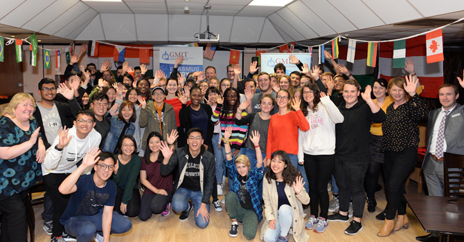 A group of students smiling and waving to camera