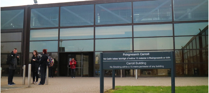 Glass fronted university building, sign in front reads Carroll building 