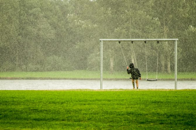 person sitting on a swing in the rain 