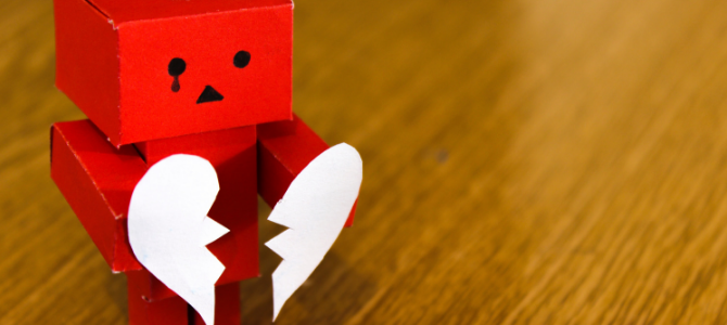 toy robot holding a broken paper heart