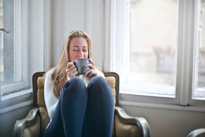 Woman sat in an armchair drinking from a mug 