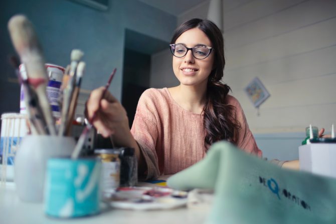 woman painting surrounded by paintbrushes