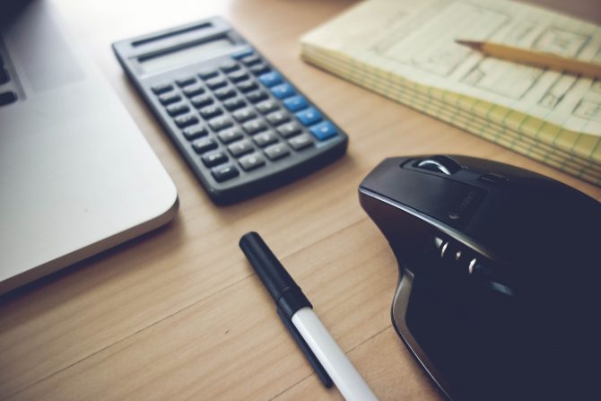 desk with calculator, computer mouse, pen and notepad 