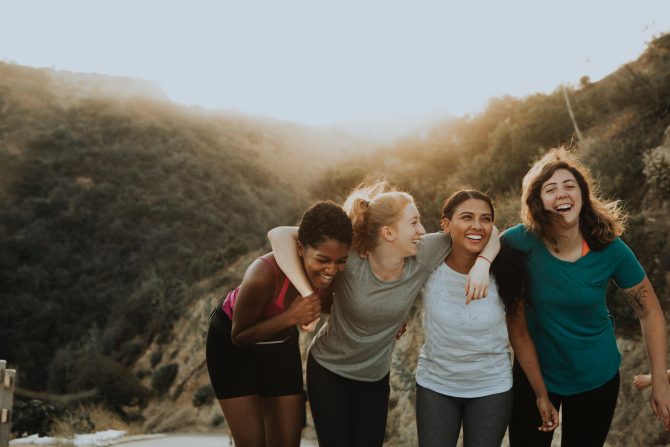 group of female friends with arms around each other smiling 