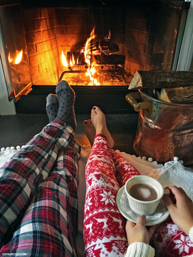 couple in pyjamas sitting by a fire 