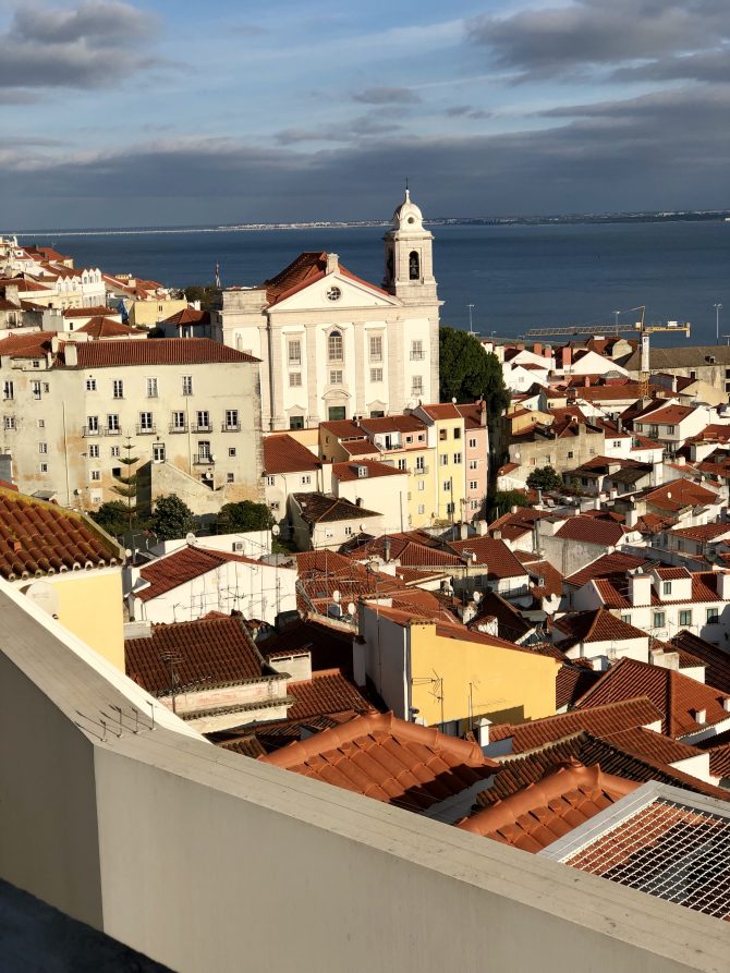 White buildings with red tiled roofs with the sea in the background 