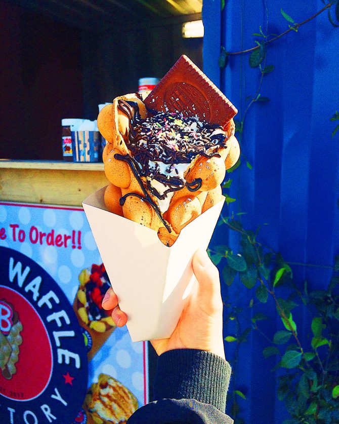 hand holding a bubble waffle with ice cream and chocolate sprinkles 