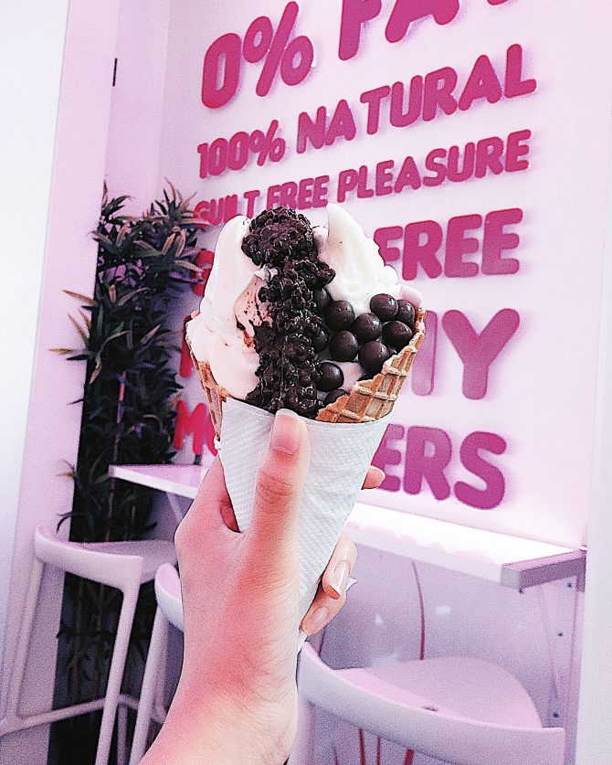 Hand holding frozen yoghurt in front of a sign with nutritional information 