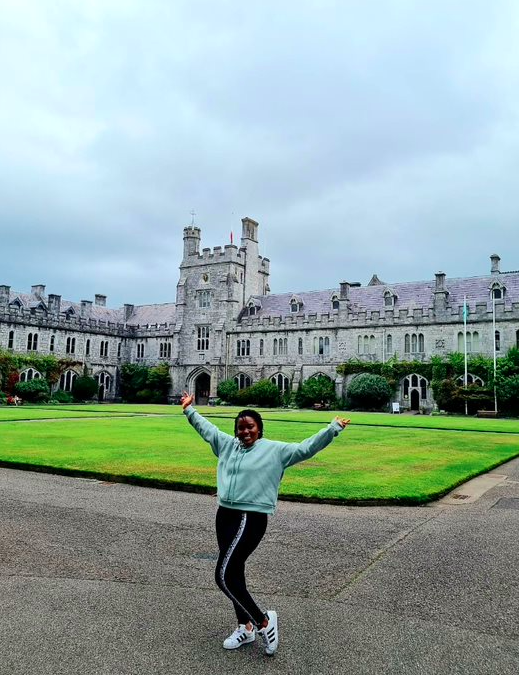 A girl with her hands up in front of a historic building